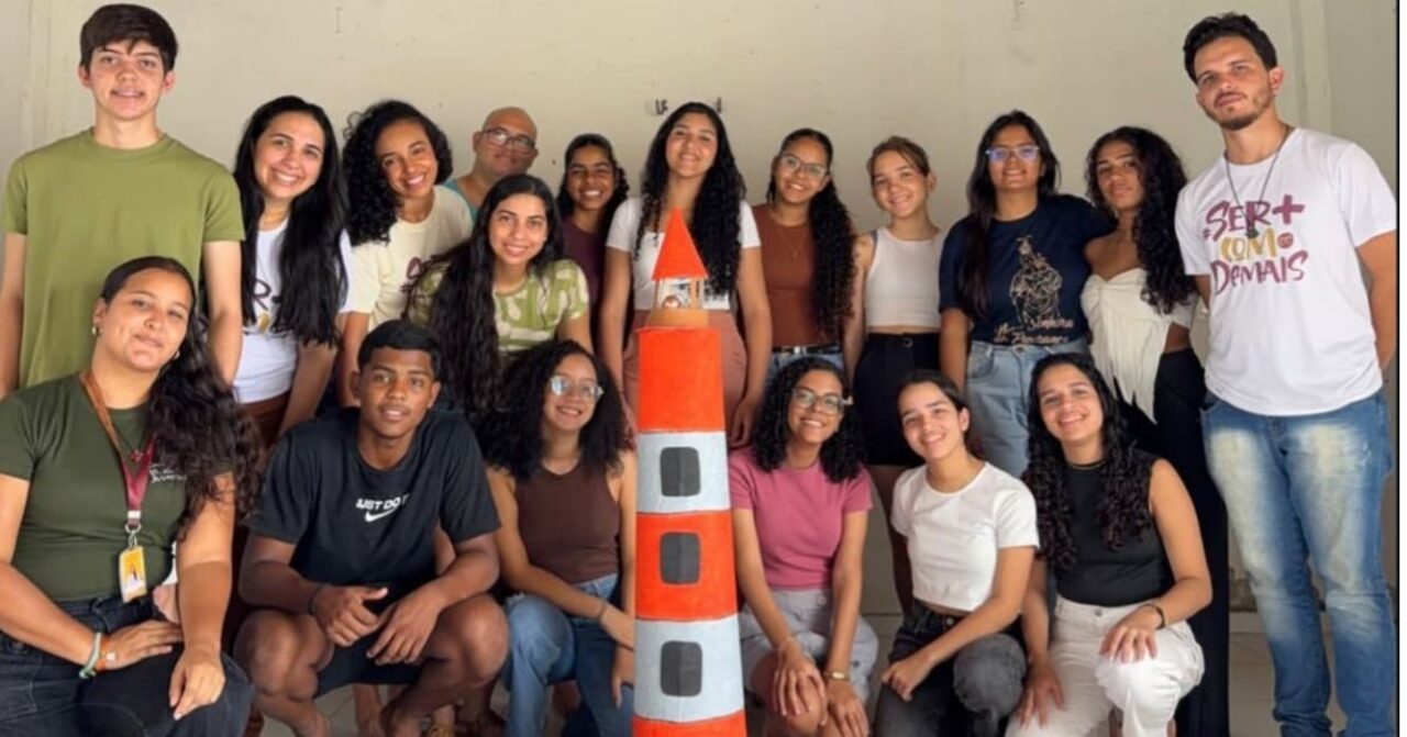 Grupo de jovens e adultos reunidos em torno de uma maquete de farol, durante atividade do Projeto Farol em Natal (RN).